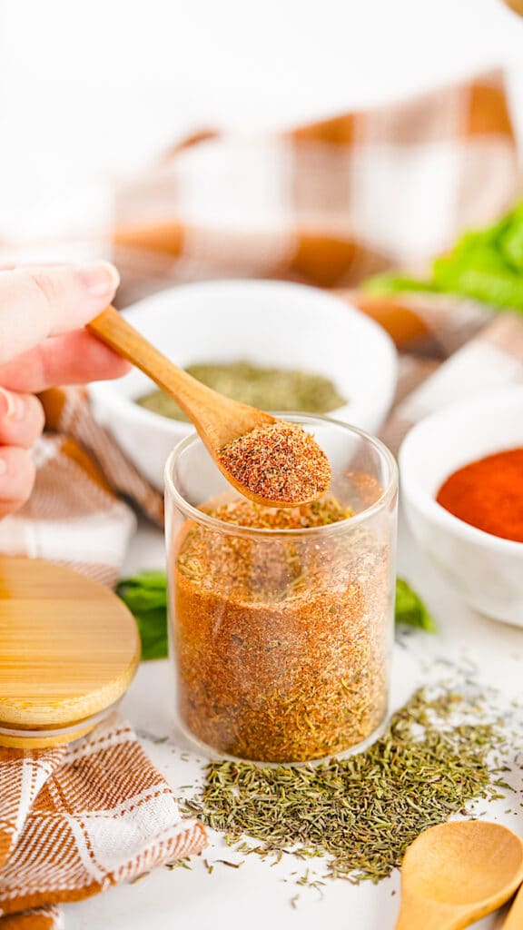 Turkey Rub in a clear jar with a person holding a wooden spoon of the rub