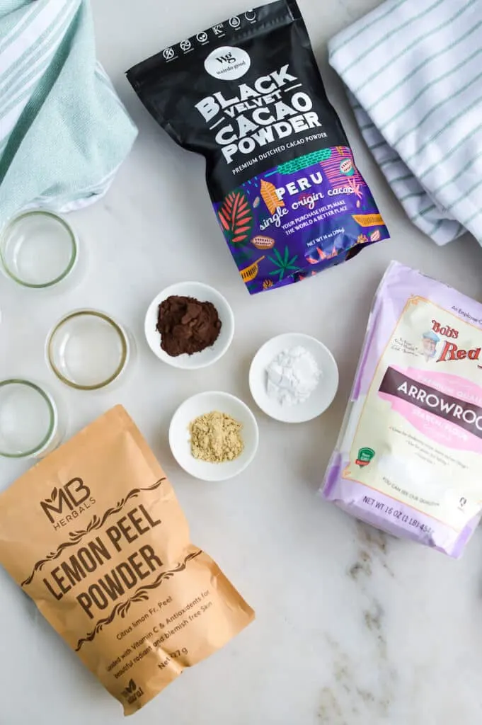 The ingredients for a DIY Dry Shampoo for dark hair recipe are laid out on a marble table.