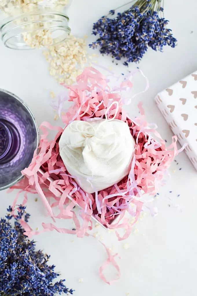 Lavender and a linen bag of Oat Bath Soak on a white table.