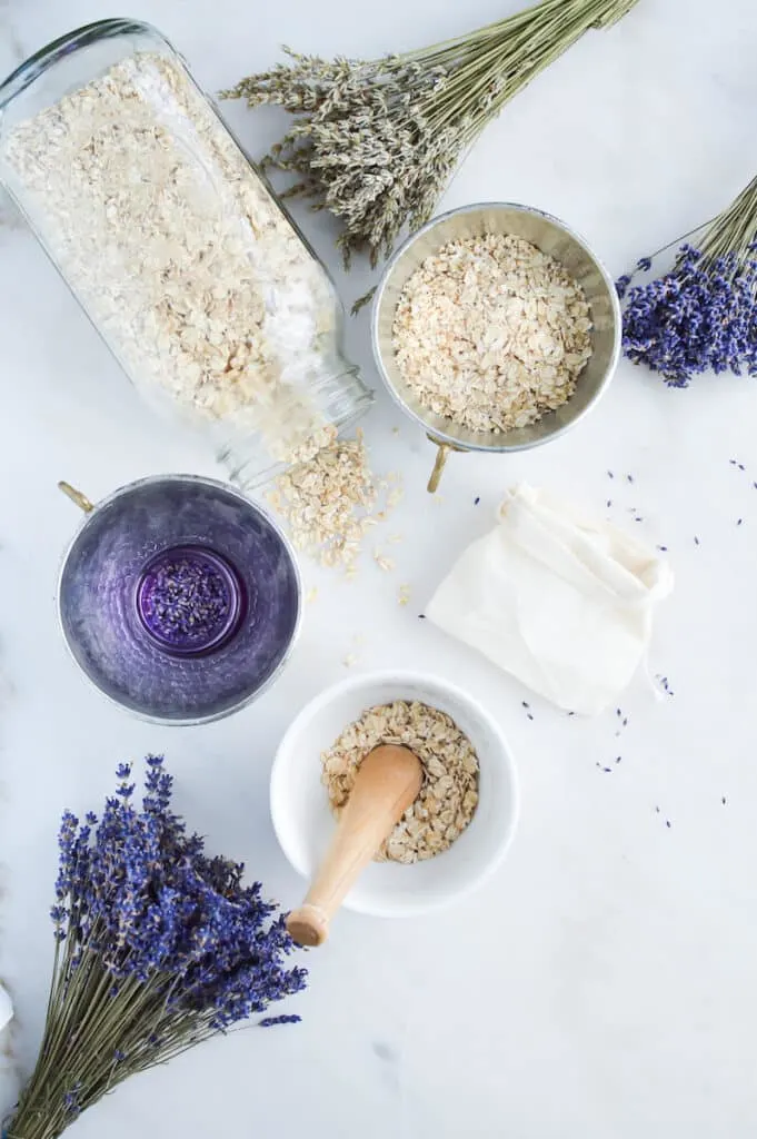 A bowl of oats, lavender flowers and a wooden spoon used for making Oat Bath Soak.