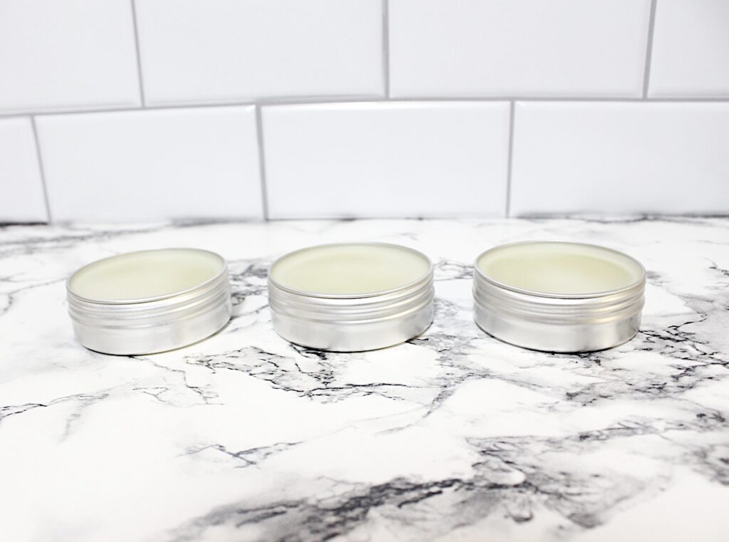 Rosemary Salve Step 4 with three tins of lip balm sitting on a marble counter.