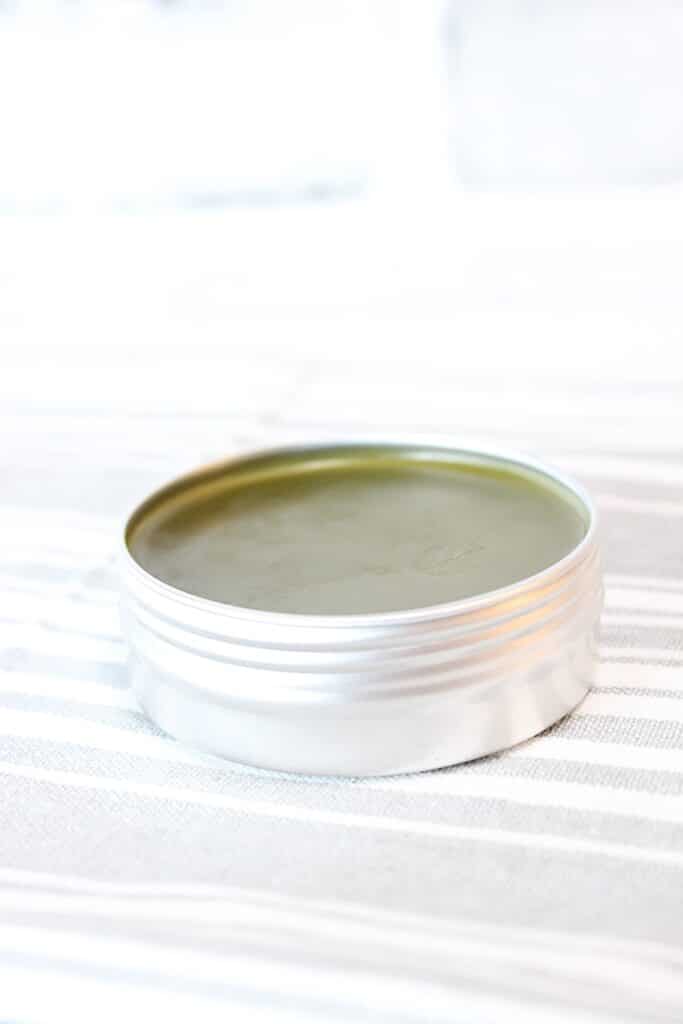 Comfrey Salve in a metal tin a grey and white striped towel