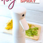A white spray bottle with a spout on a cutting board.
